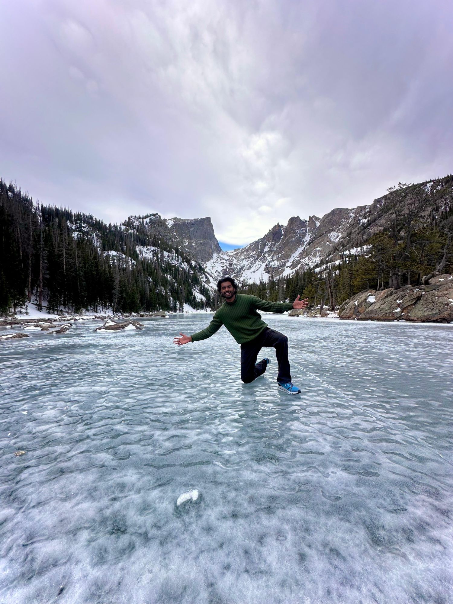 Pavan standing on a frozen alpine lake in Rocky Mountain National Park, Colorado